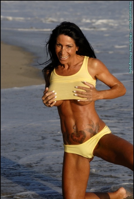 Dark-haired bodybuilder Ava Jordan flexes while exposing herself on a beach