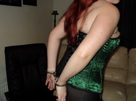 Chubby redhead sports a cleave gag with her wrists handcuffed behind her back