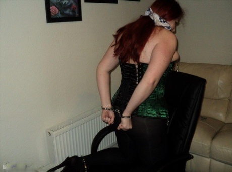 Chubby redhead sports a cleave gag with her wrists handcuffed behind her back