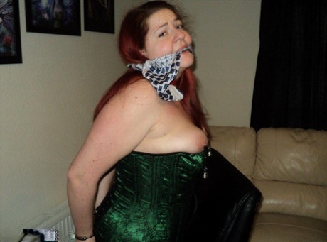 Chubby redhead sports a cleave gag with her wrists handcuffed behind her back
