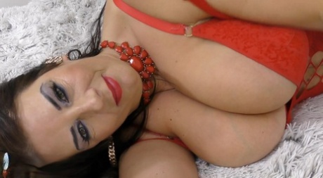 Mature lady Lulu oils up her large tits during solo action while at home