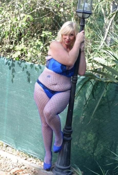 Blonde granny Melody touches her huge tits outdoors in a mesh bodystocking