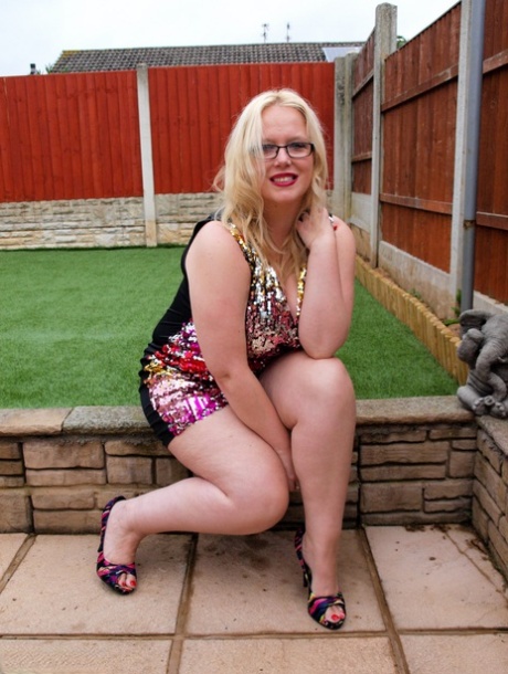 Overweight UK blonde Sindy Bust gets naked on a retaining wall in a backyard
