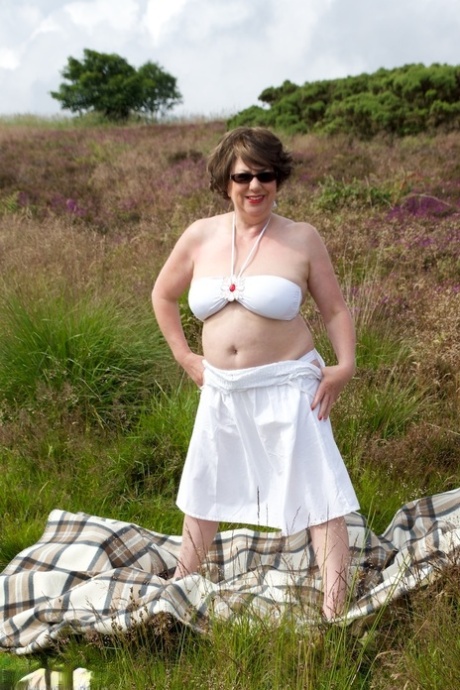 Mature lady Dirty Doctor goes topless on a blanket in a field