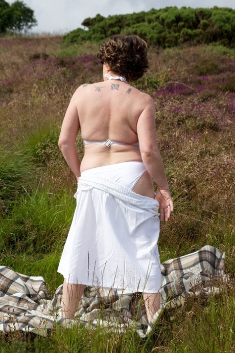 Mature lady Dirty Doctor goes topless on a blanket in a field