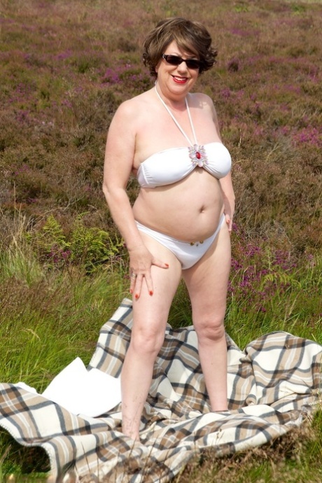 Mature lady Dirty Doctor goes topless on a blanket in a field