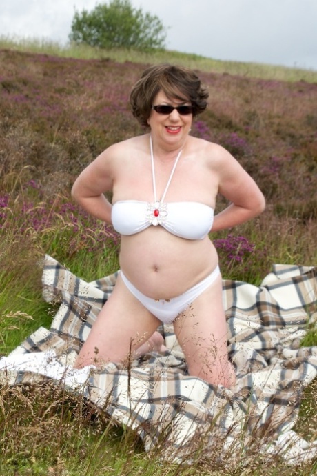 Mature lady Dirty Doctor goes topless on a blanket in a field