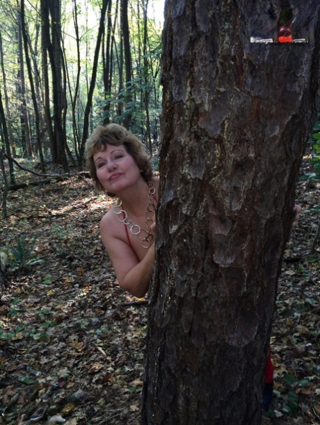 Older lady Busty Bliss gets completely naked while in a forest