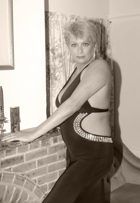 Mature blonde Dimonty holds her bare ass after freeing her tits and twat