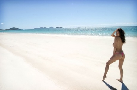 Busty Asian model Tera Patrick removes bikini bottoms to pose nude in the sea