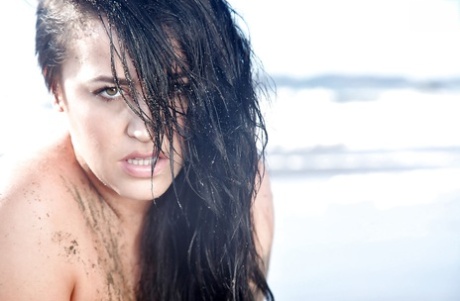 Chesty brunette pornstar Leanne Crow exposing huge hooters on the beach
