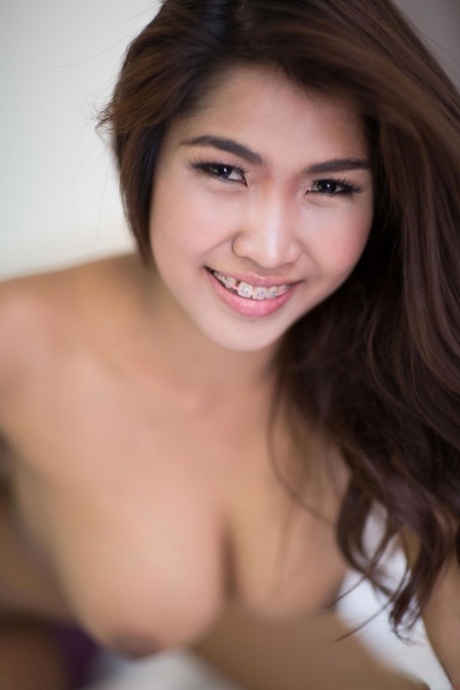 Beautiful Asian teen Tittiporn teases with her big tits on her bed