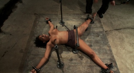 Black female sub Mia Stiletto gets fucked with a vibrator in metal bondage